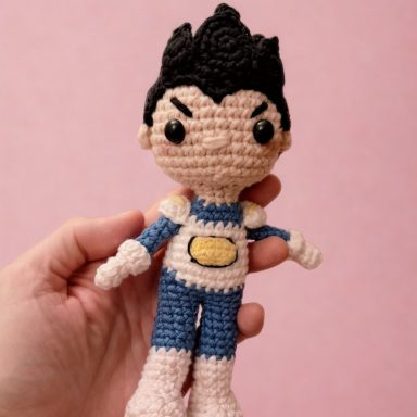 Muñeco de crochet con cabello negro y traje azul y rosa.